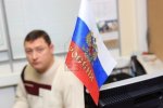 Man is sitting in office with a floating Russian Flag in the foreground.